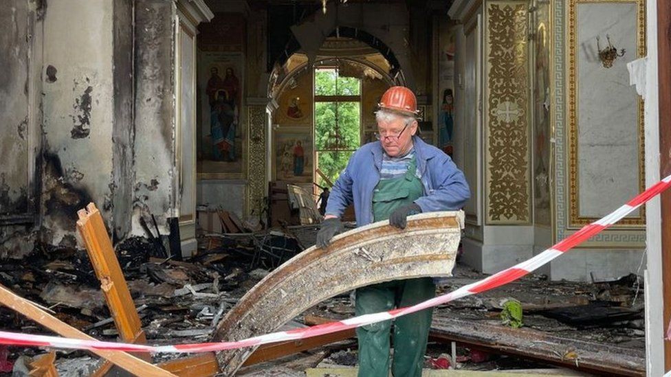 Man clears rubble from a bombed cathedral in Odesa