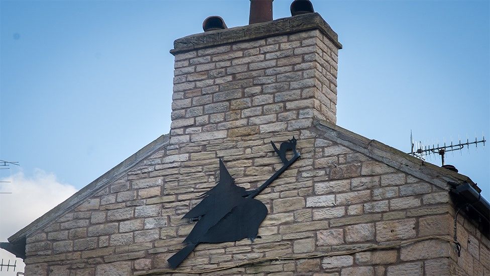 Witch on a broomstick on the external side of a house in Roughlee