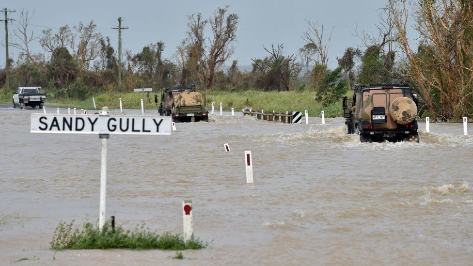 Australian Defence Force vehicles move through shallow floodwaters near Bowen in Queensland