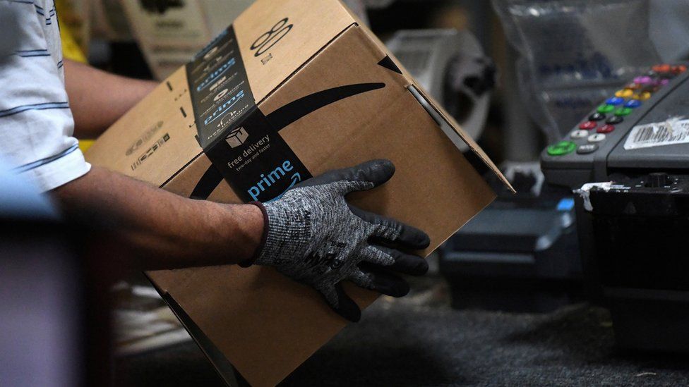 An Amazon worker preps a box for delivery at a warehouse