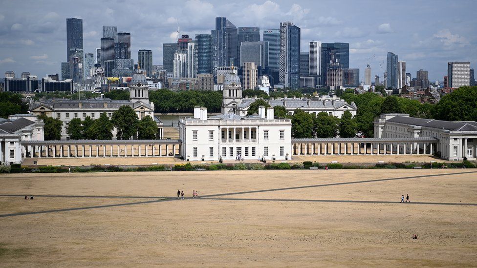 Parched grass in front of the naval college in Greenwich, London. Canary Wharf is seen in the background