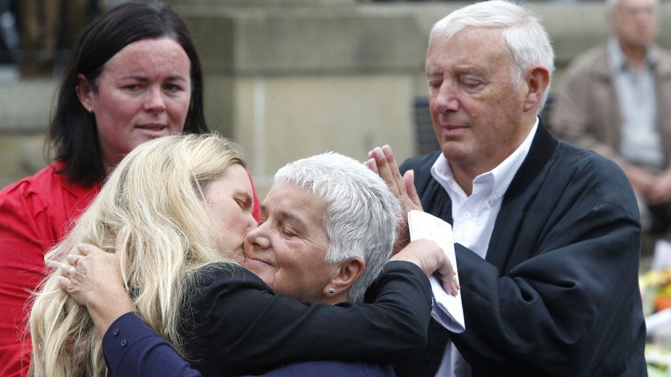 Jean Leadbeater, the mother of Labour MP Jo Cox, embraces her sister Kim Leadbeater while her father Gordon looks on, as they look at floral tributes left in Birstall, West Yorkshire