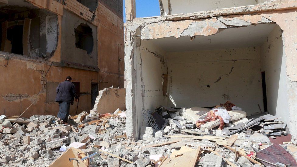 A man walks between debris following clashes in Libya
