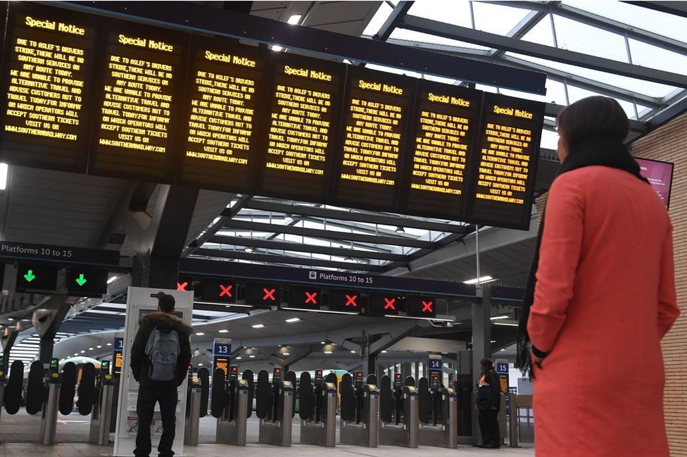 Commuters look on at blank departure boards