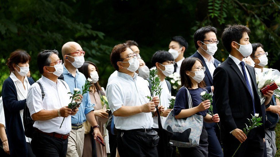 People line up to offer flowers as they attend the funeral of late former Japanese Prime Minister Shinzo Abe at Zojoji Temple in Tokyo, Japan July 12, 2022.