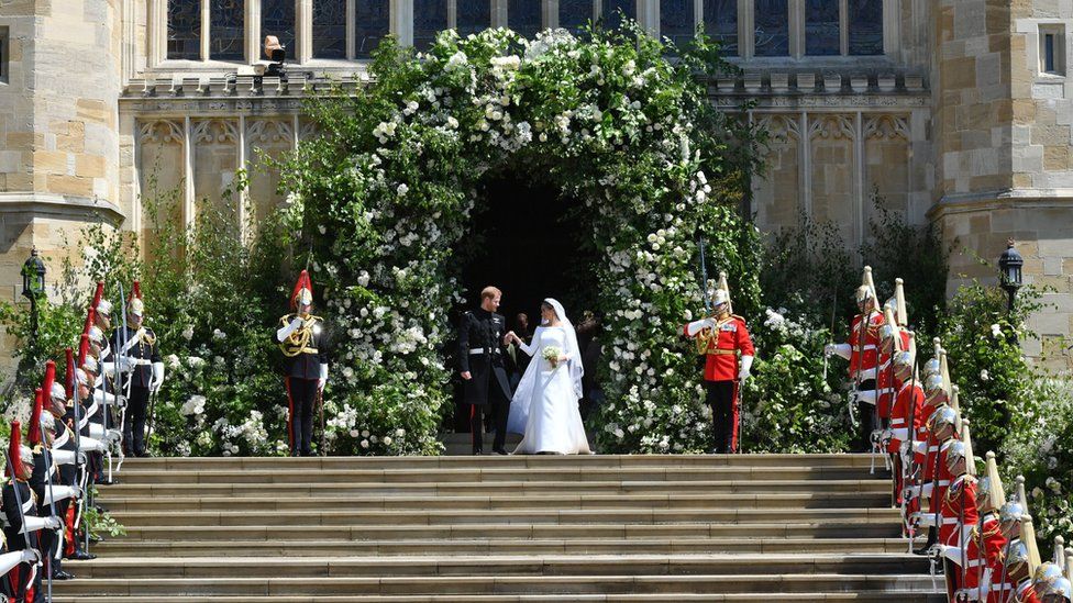 Prince Harry and Meghan Markle leave St George's Chapel though a gateway of flowers.