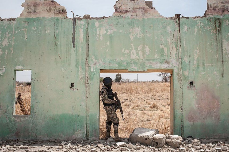 A soldier stands next to the ruins of Government Girls Secondary School Chibok in 2016.