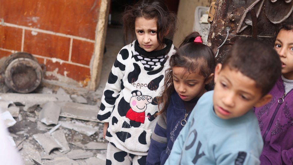 Palestinian children look on at the site of an Israeli strike on a house