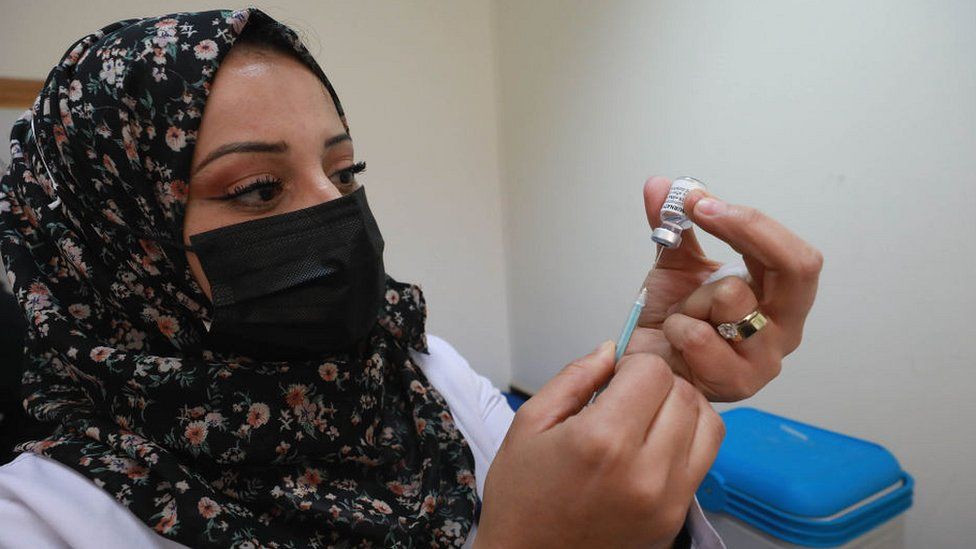 Palestinian health worker holding up vaccine vial