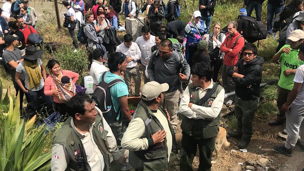 Passengers and crew stand along the railway track after two tourist trains crashed near the Inca citadel of Machu Picchu