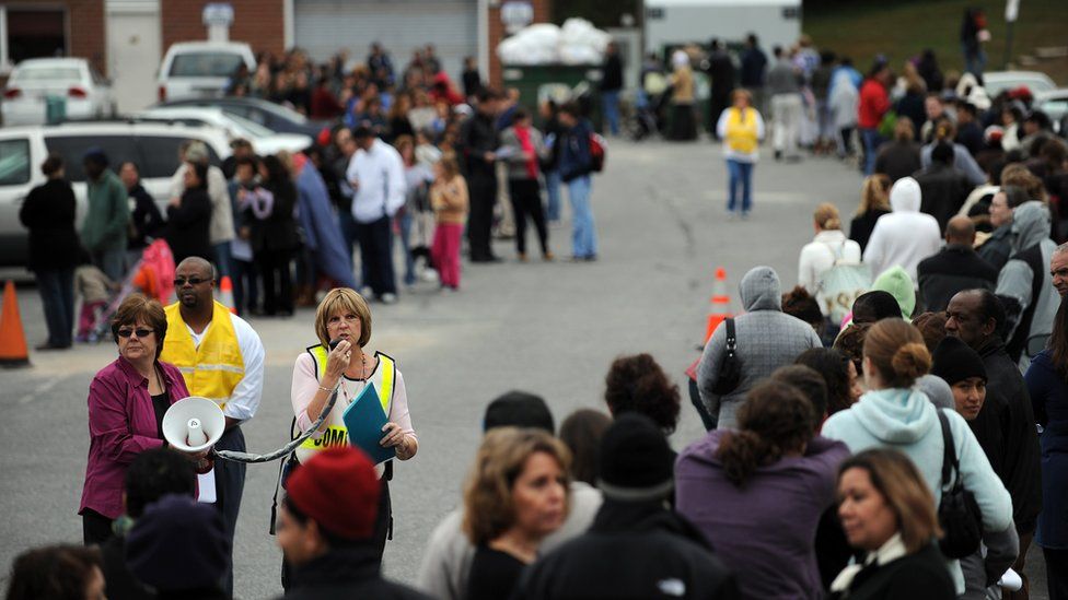 Healthcare workers make announcements to residents waiting in a long line for a vaccination shot in 2009