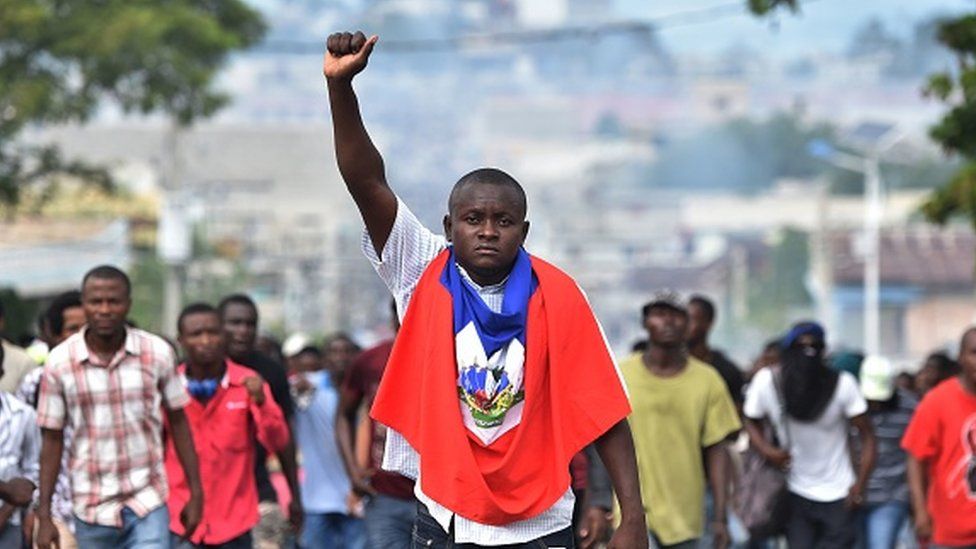 A man holds up his fist as demonstrators march through the streets of Port-au-Prince