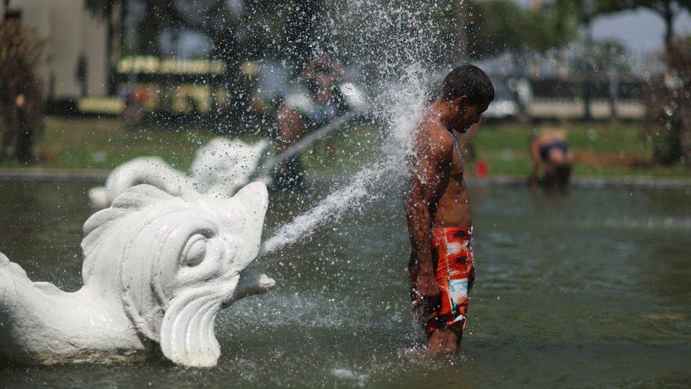 A man cools down in a fountain during a heatwave in Rio de Janeiro