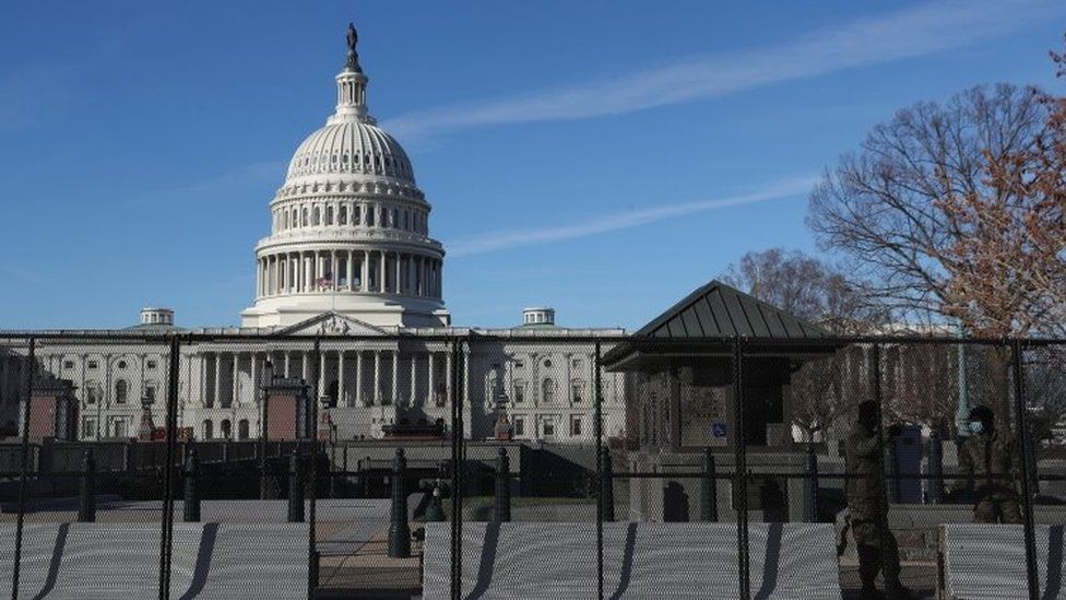 Members of the National Guard stand next to a fence and barricades set up around the U.S. Capitol building in Washington