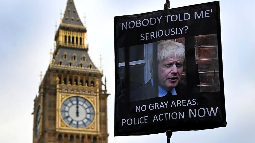 A protester holds a placard showing British Prime Minister Boris Johnson, outside parliament in London, 19 January 2022