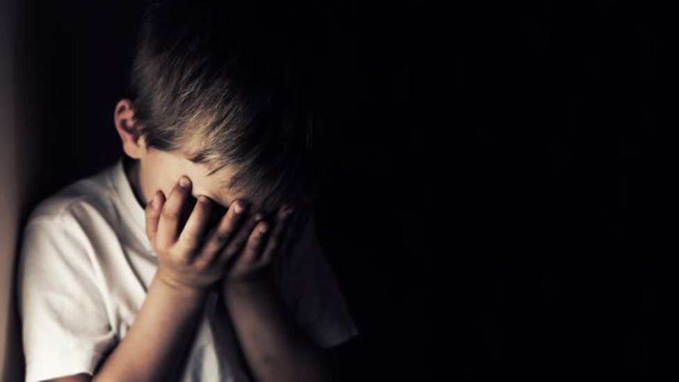 An image of a sad child, head in hands