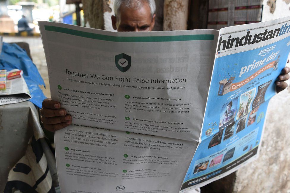An Indian newspaper vendor reads a newspaper with a full back page advertisement from WhatsApp intended to counter fake information in Delhi on July 10 2018.
