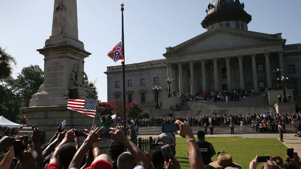 A crowd cheers as a South Carolina state police honour guard lowers the Confederate flag from the Statehouse grounds in Columbia, South Carolina - 10 July 2015