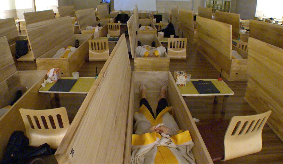 Employees lying in coffins