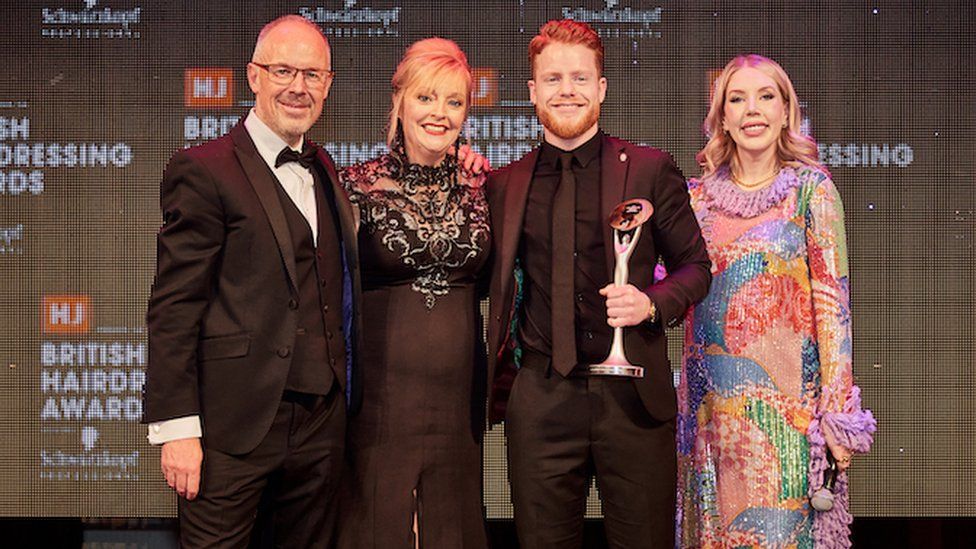 A group of four in black tie dress, including award-winner George Smith with trophy.