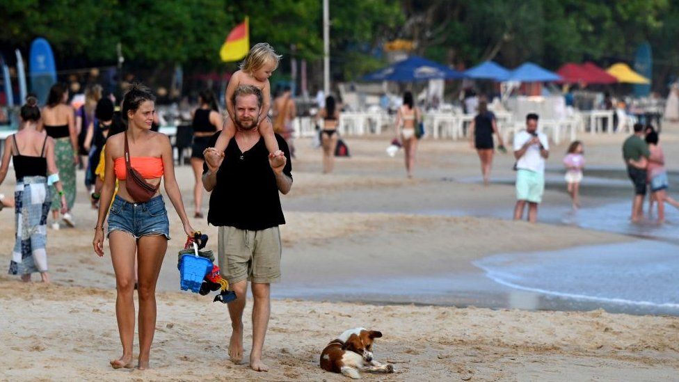 Family of three walk on Sri Lankan beach
