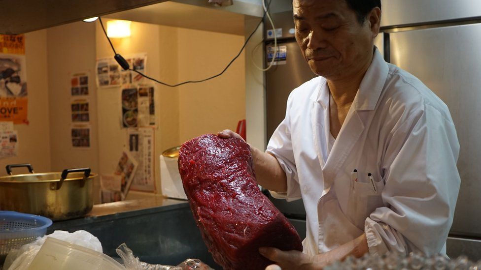A chef in a whale meat restaurant in Tokyo showing off a chunk of red meat
