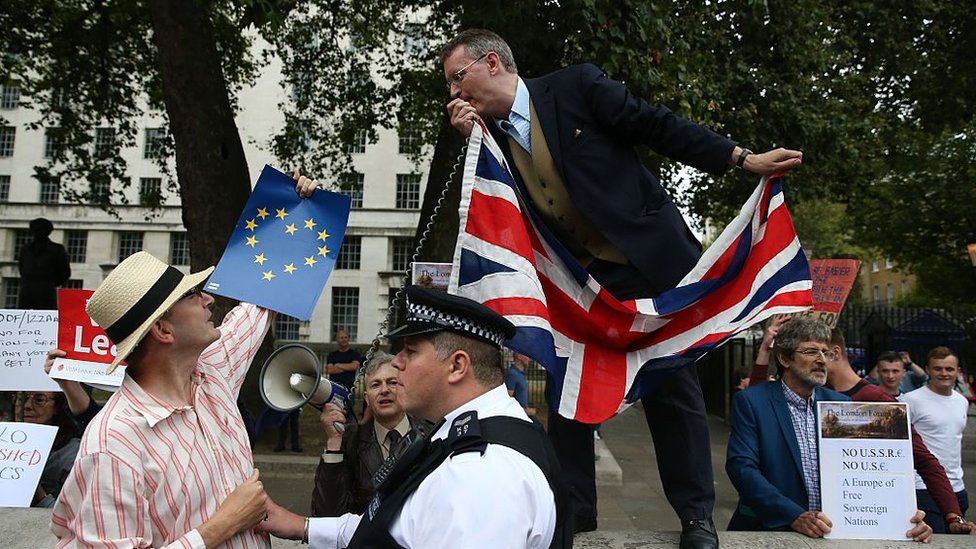 A police officer separates a pro-Europe anti-Brexit demonstrator from a pro-Brexit demonstrator