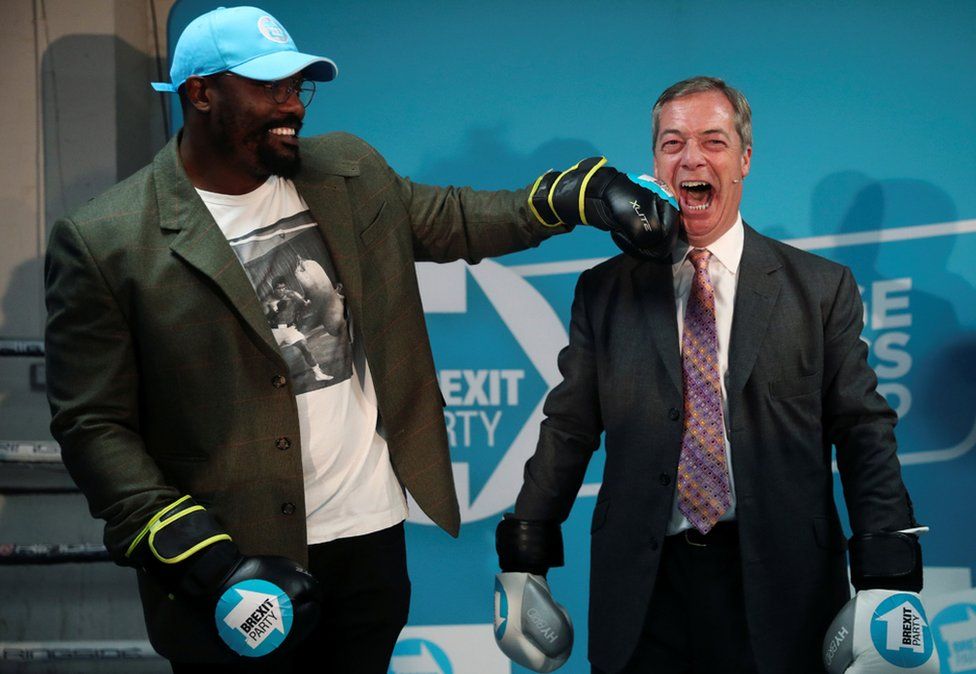 Brexit Party leader Nigel Farage poses with boxer Dereck Chisora during a visit to a boxing gym in Ilford, Essex.