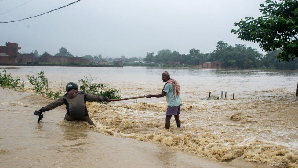 Nepali residents use a stick to help each other cross a flooded area in the Birgunj Parsa district of the country.