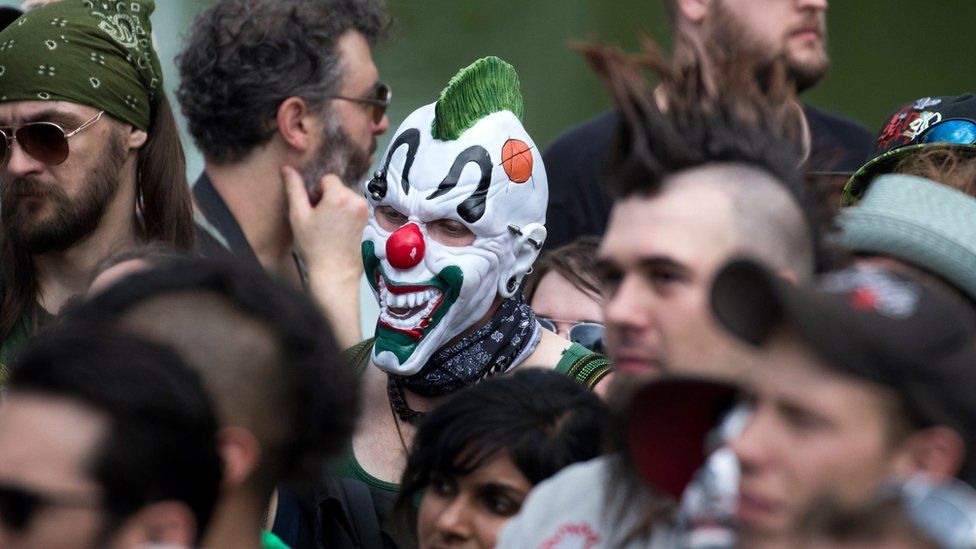 A man in a clown face stands in the midst of the protest