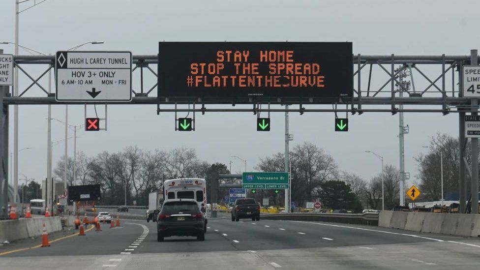 Cars drive under an electronic sign board warning drivers about coronavirus, COVID-19,on a highway near the Verrazano Bridge on March 30, 2020 in New York.