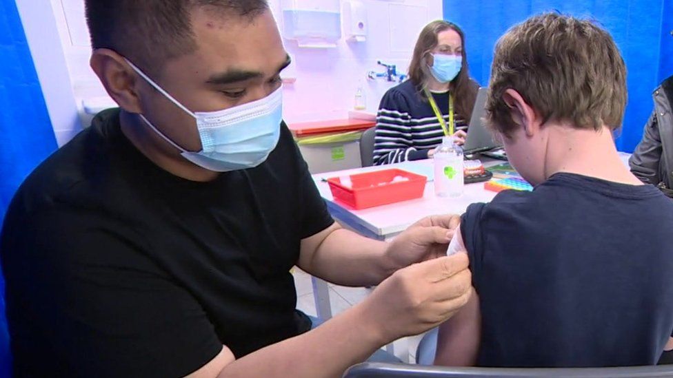 Two medics giving a child a jab at a vaccination clinic