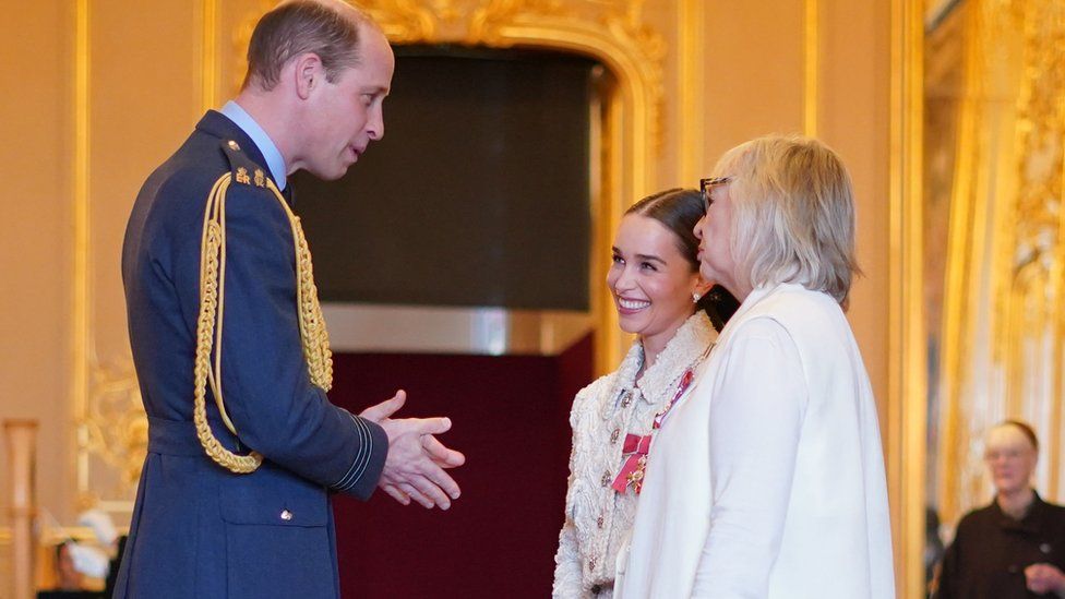 Prince William talks to Emilia and Jenny Clarke after awarding them with their MBEs