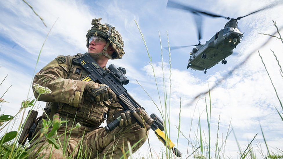 A solider maintains the perimeter as a Chinook helicopter carries out a medical evacuation during a military exercise