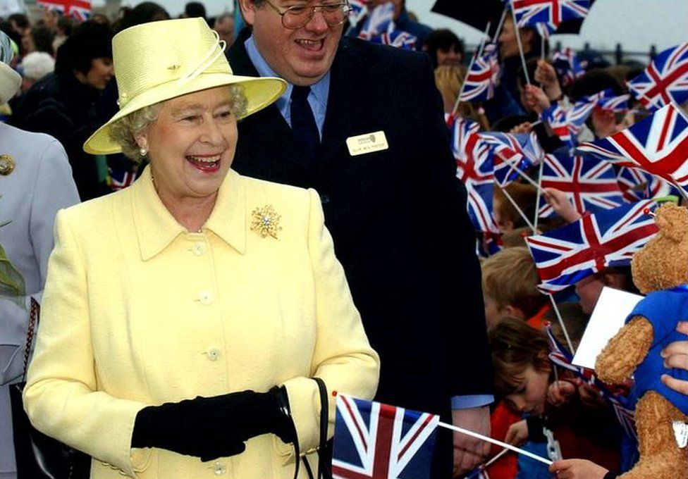 Queen laughs as she is offered a teddy bear from one of the young schoolchildren who greeted her as she arrived at Seaham, Sunderland on 8 May, 2002.