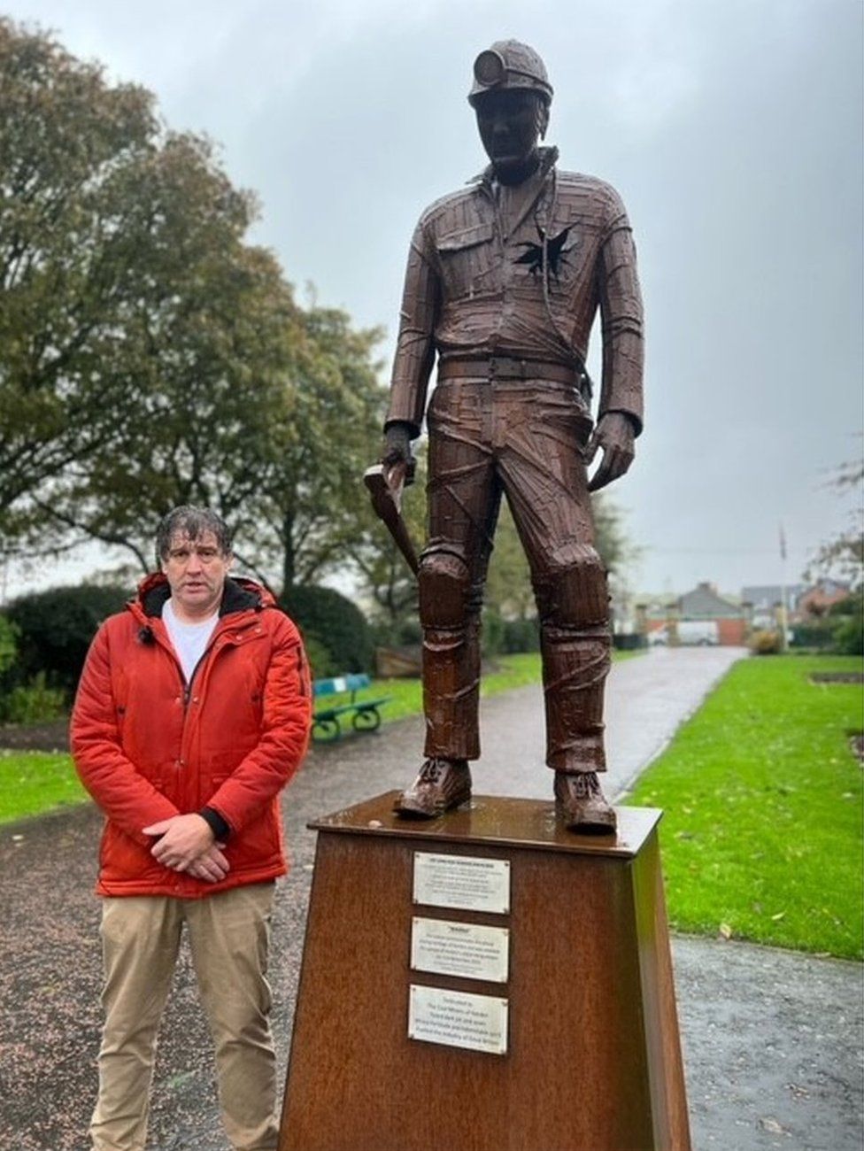 Pip Fallow alongside a statue of a coal miner with his heart ripped out, symbolising the loss of heavy industry in the area