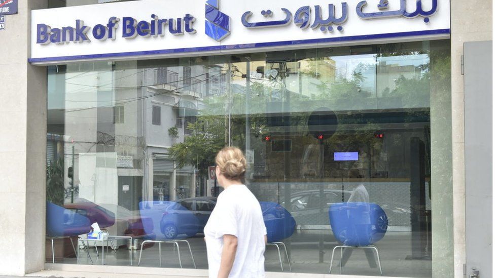 Man walks in front of branch of Bank of Beirut