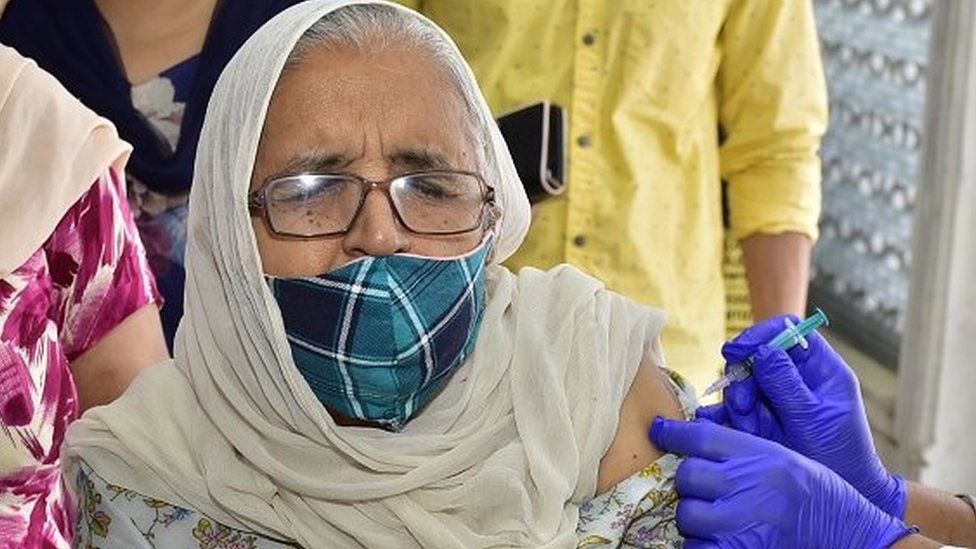 A medical worker administers a dose of vaccine to a beneficiary at a vaccination camp.