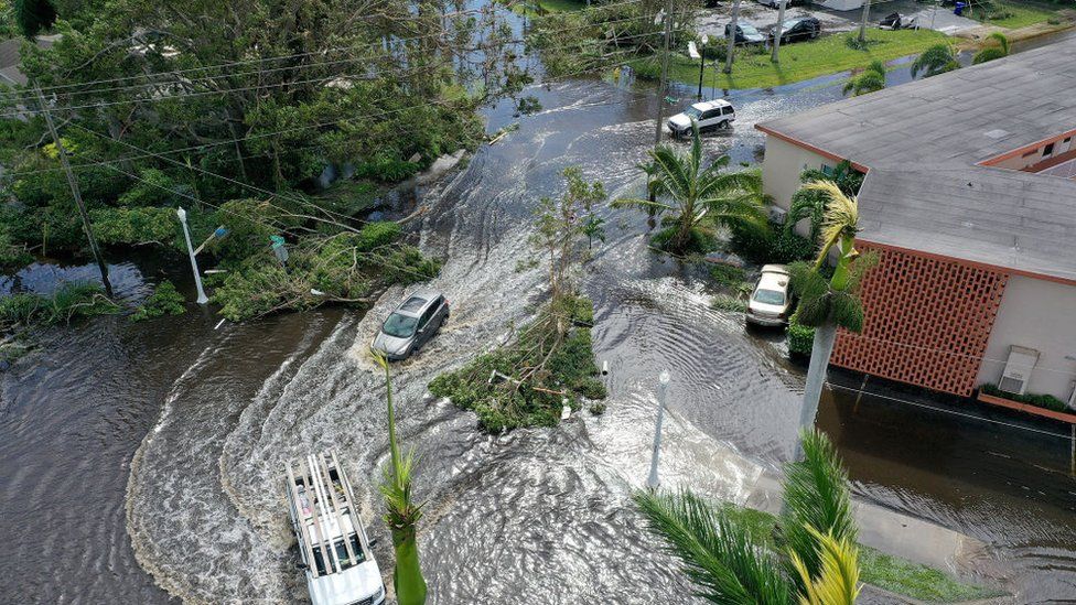 Aerial view of vehicles try to drive through flooded street after Hurricane Ian.