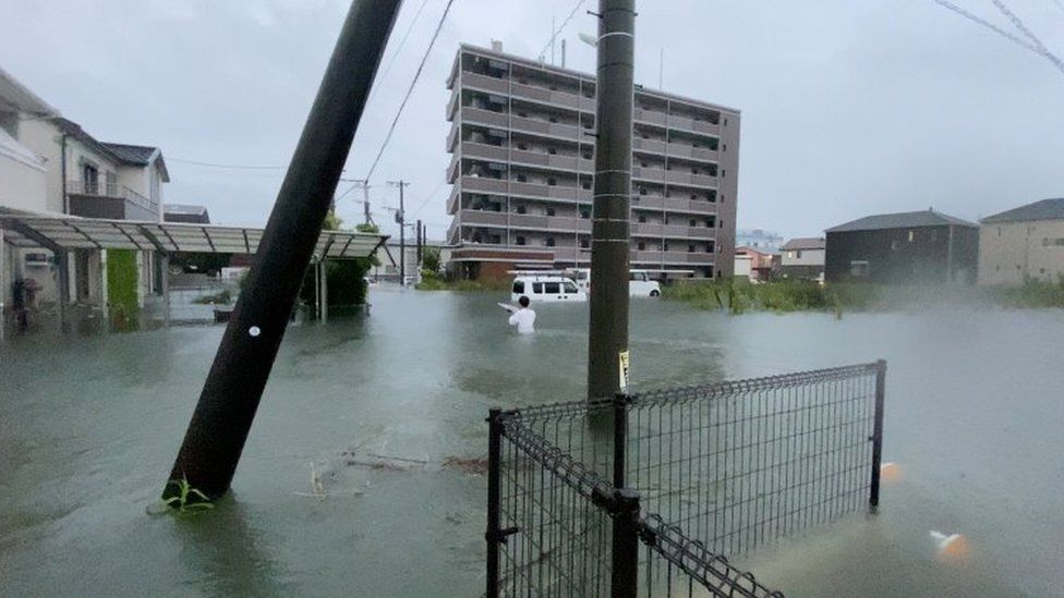 A person walks at a flooded area during heavy rain in Kurume, Fukuoka Prefecture