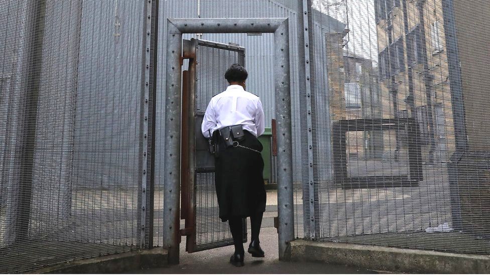 A prison guard opens a gate