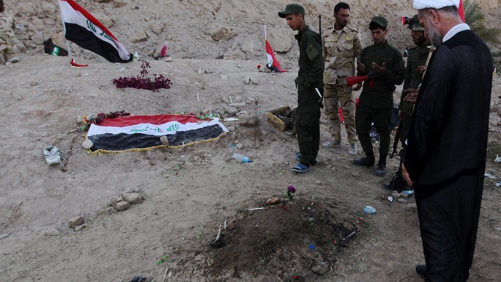 Iraqi Shia fighters examine a burial site thought to hold victims of the Camp Speicher massacre