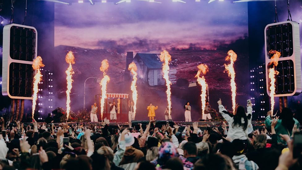 Flames fire behind a performer and dancers on stage at Parklife