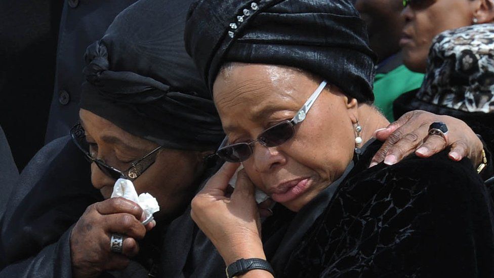ex-wife of Nelson Mandela, Winnie Mandela Madikizela (L), and his widow Graca Machel wipe their tears upon their arrival with the remains of South African former president Nelson Mandela at the airport in Mthatha on December 14, 2013.