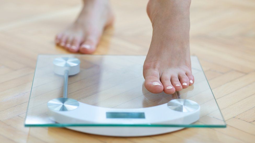 woman stepping onto the scales