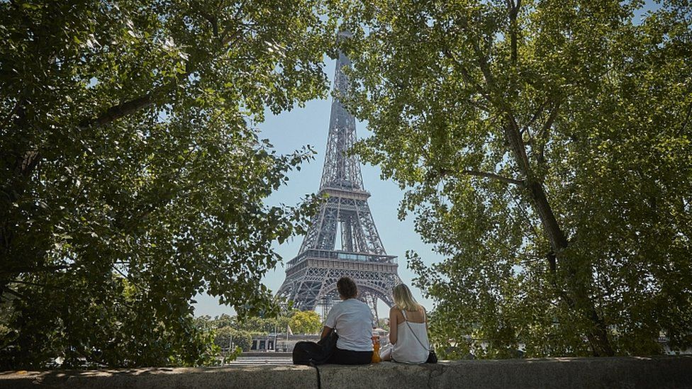 Tourists relax in the shade overlooking the Eiffel Tower. 25 June