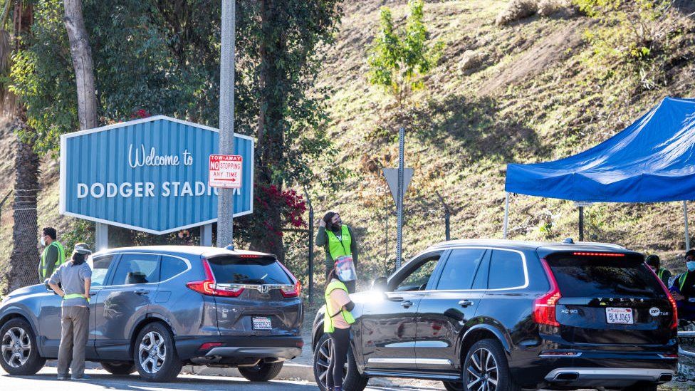 employees direct traffic at Dodger Stadium in Los Angeles after it was turned into a COVID-19 drive-thru vaccination site
