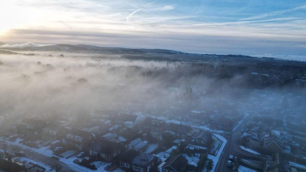 Fog drifting over a residential area with snow lying on the ground