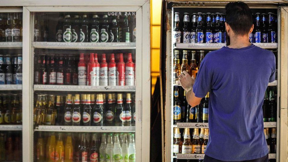 A shopworker arranges beer bottles in a refrigerator at a liquor shop in the Bataween district in the centre of Iraq's capital Baghdad on 5 December 2020