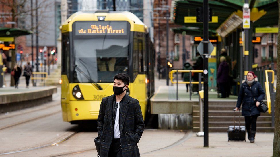 People walk past tram tacks in Manchester